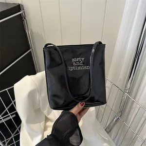 Minimalist black glossy faux leather tote bag with white lettering for women's daily commute