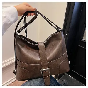 Close-up of vintage brown PU leather texture and silver buckle detail on large tote bag