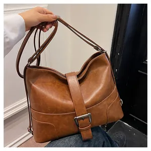 Close-up of vintage brown PU leather tote bag with vertical strap and metal buckle