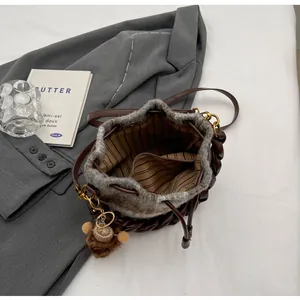 Détail du sac seau à cordon avec garniture en peluche, doublure rayée et charme d'ours
