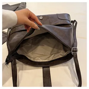 Detail showing the inner structure, zip pocket, and beige lining of the brown tote bag