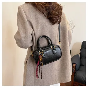 Détail d'un sac à main en cuir PU noir texturé avec boucles dorées et pendentif chic