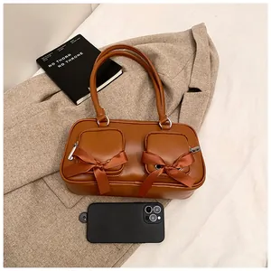 Detailed view of a brown ballet-style shoulder bag with bow-decorated front pockets