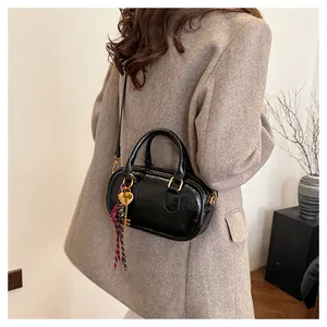 Détail du sac à main en cuir verni noir avec pendentif cœur et foulard décoratif