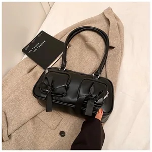 Detail of black PU leather shoulder bag featuring ribbon bows and functional zippers