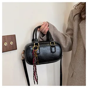 Détail du sac à main en cuir huilé noir avec ferrures dorées et accessoire de gland