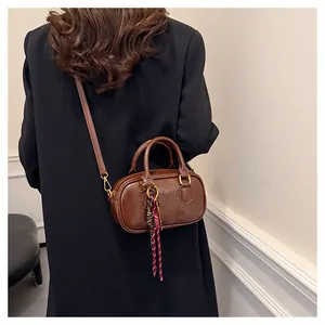 Vue détaillée du sac Boston en cuir marron foncé porté par le mannequin avec ruban