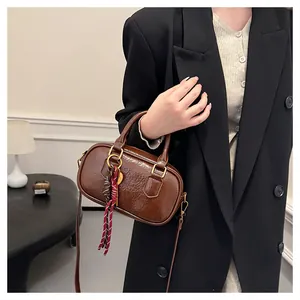 Détail du sac Boston marron foncé en cuir brillant avec ruban à carreaux rouges