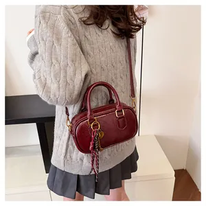 Vue détaillée du sac boston en cuir bordeaux avec breloque en corde et ornement de clé