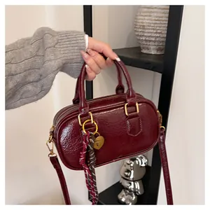 Détail du sac à main bordeaux en cuir synthétique ciré avec fermoir cœur doré et ruban