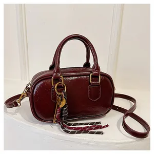Détail du sac Boston bordeaux en cuir verni avec breloques de cadenas cœur en métal