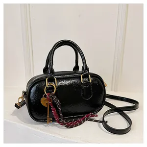 Détail du sac Boston noir en cuir froissé avec quincaillerie dorée et pendentifs