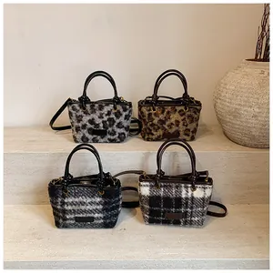 Close-up of four plaid and leopard plush mini crossbody bags on stone steps
