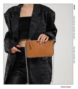 Detail shot of brown woven leather bag with silver chain strap and metal rivet trim