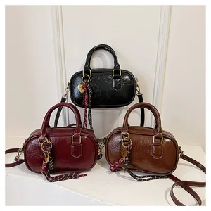 Trois sacs à bandoulière en cuir PU brillant de couleur noir, bordeaux et marron