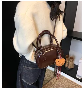Detail view of glossy dark brown patent leather handbag with bear charm decoration