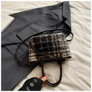 Close-up of black and white plaid wool bag with brown leather handles and gold hardware