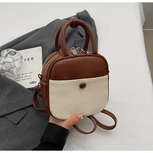 Détail d'un mini sac à dos en similicuir marron et beige avec double poignée et bretelles