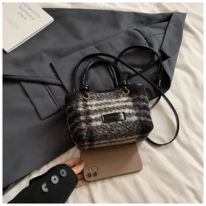 Macro detail of plaid tweed crossbody bag with black leather handle and shoulder strap