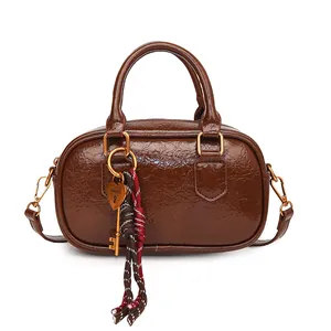 Sac Boston en cuir verni marron avec pendentif cœur doré et détails de cordons tressés