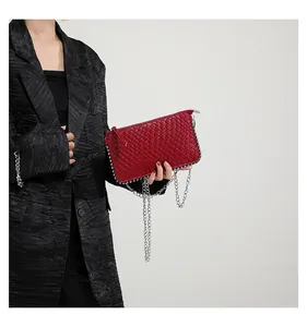 Detail of red woven texture handbag with silver chain strap on black blazer background