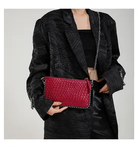 Detail of dark red crocodile textured handbag with silver rivets and chain strap