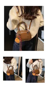 Detail view of a vintage brown Boston bag with shoulder strap and plush bear charm