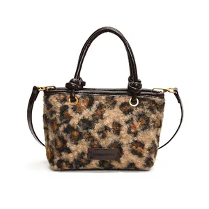 Leopard print plush tote bag with dark brown leather straps and adjustable shoulder belt