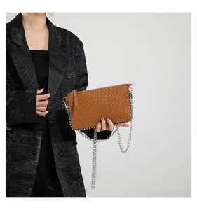 Brown woven crossbody bag with silver chain strap shown against a black blazer