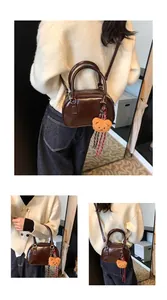 Detail view of dark brown glossy leather bowling bag with cute plush bear charm