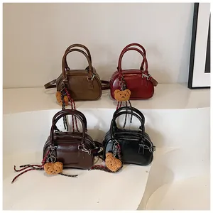Collection of four vintage PU leather mini Boston bags with bear charms on white steps