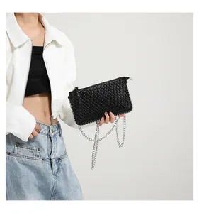 Close-up of black woven texture and silver metal chain strap on minimalist bag