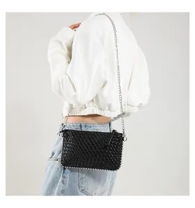 Detail of black woven shoulder bag featuring silver rivet trim and metal chain strap