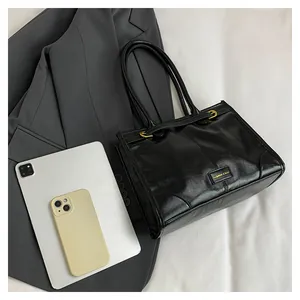 Detailaufnahme der schwarzen Leder-Tote-Bag mit goldenen Metallbeschlägen und Textur
