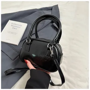 Close-up of a mini black cylinder handbag with high-gloss finish and silver hardware