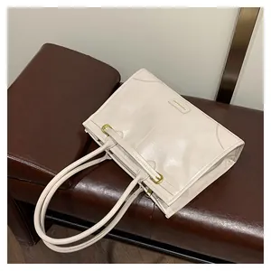 Detail der cremeweißen Kunstledershopper mit goldener Hardware und geprägtem Modelogo