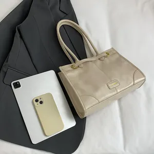 Große khakifarbene Vintage-Einkaufstasche mit Metalllogo und Bürozubehör auf Sakko