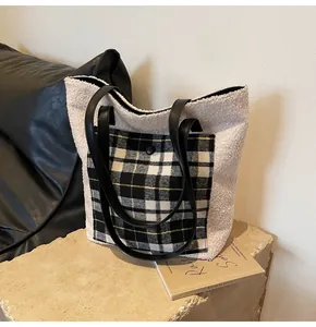 Detail of plush fleece tote bag featuring a checkered pocket and black leather strap
