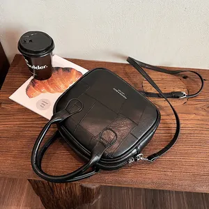 Schwarze Vintage-Patchwork-Henkeltasche mit abnehmbarem Gurt auf einem Holztisch