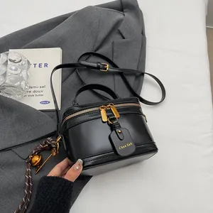 Vintage black bucket bag with dual zippers and leather handle against gray blazer