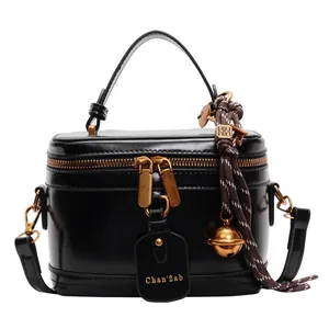 Retro black glossy bucket handbag with gold zippers and decorative woven tassel