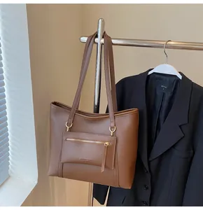 Detail einer braunen Leder-Tragetasche mit einer Reißverschlusstasche und feinen Nähten