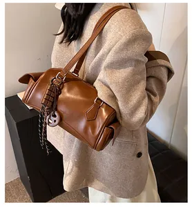 Détail d'un sac bandoulière vintage en cuir marron sur un blazer avec pendentif chic