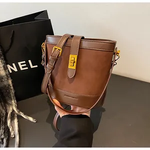 Détail du sac seau en daim marron avec fermoir doré et bandoulière en cuir