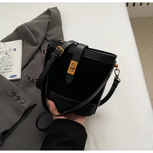 Détail du sac seau noir en cuir avec fermoir rotatif doré et bandoulière réglable