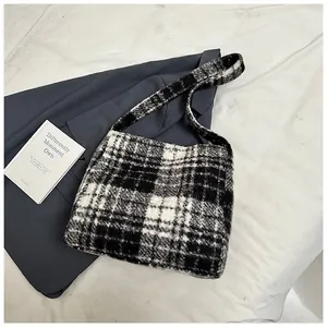 Close-up of black and white plaid fuzzy tote bag on blue blazer with thick soft texture
