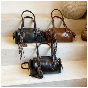 Trois sacs Boston en cuir noir, caramel et marron posés sur des marches en pierre