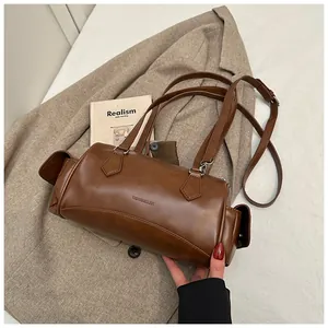 Détail d'un sac à main cylindrique en cuir marron foncé vintage sur une veste de costume