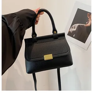Détail du sac à main en cuir grainé noir avec fermoir doré et bandoulière fine
