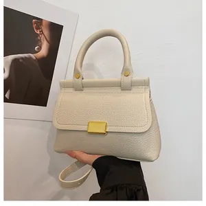 Gros plan sur la texture cuir litchi crème et le fermoir en métal doré du sac